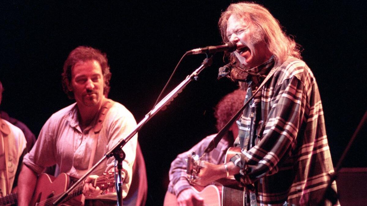 Neil Young, right, is joined by Bruce Springsteen, left, and Young's band Crazy Horse in 1995 at the Bridge School benefit concert in Mountain View, Calif.