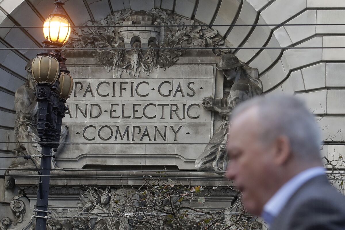 FILE - In this Dec. 16, 2019, file photo, is a man walking past a Pacific Gas and Electric sign on a PG&E building in San Francisco. PG&E's household customers will be hit with an average rate increase of 8% to help the once-bankrupt utility pay for improvements designed to reduce the risks that its outdated equipment will ignite deadly wildfires in its Northern California service territory. The higher prices, effective March 1, are expected to boost the bills of PG&E's residential customers by an average of $13.44 to per month. (AP Photo/Jeff Chiu, File)
