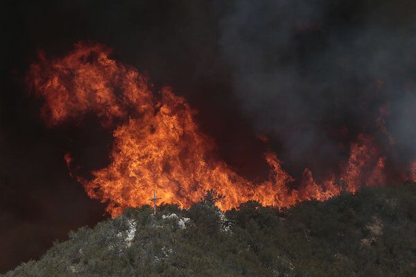 Flames move toward a cross on a hillside overlooking a religious retreat threatened by the Powerhouse fire near Castaic.