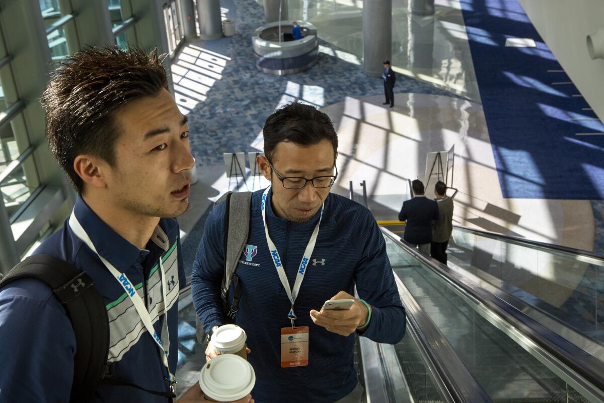 Kensuke Nakata, left, who works for Dome Corporation (Under Armour Japan) and Shinzo Yamada, senior associate athletic director at the University of Tsukuba, take the escalators to a session during the NCAA 2020 convention.