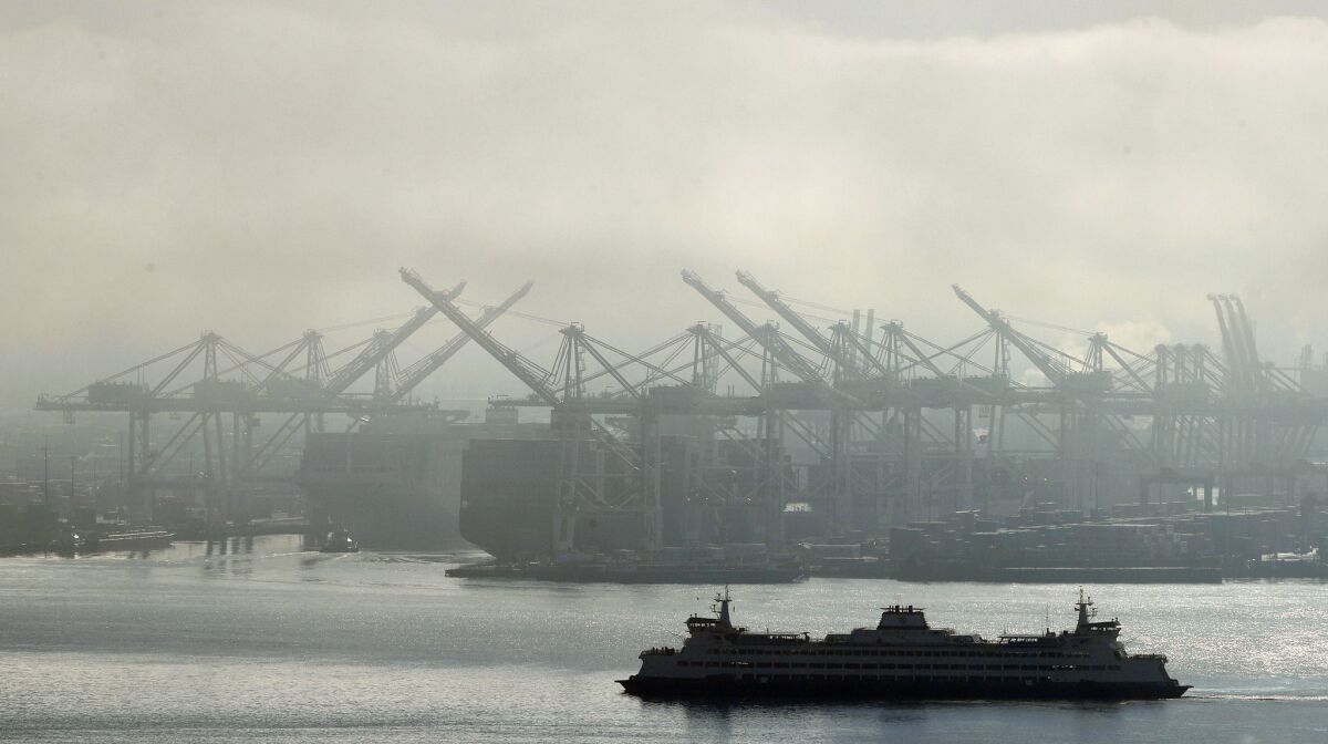 A ferry sails near cranes at the Port of Seattle.