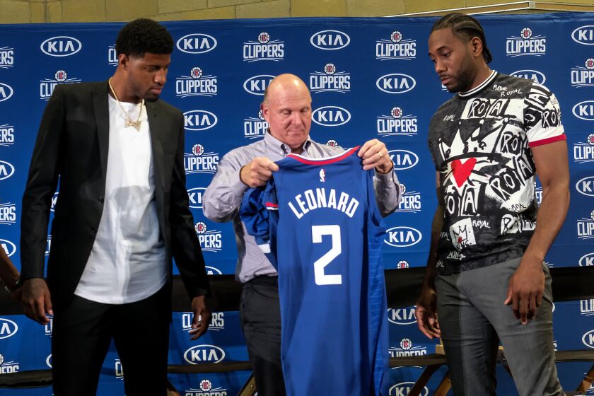 Los Angeles Clippers team chairman Steve Ballmer, center, presents a new team jersey to Kawhi Leonard, right, as Paul George looks on during a press conference in Los Angeles, Wednesday, July 24, 2019. Nearly three weeks after the native Southern California superstars shook up the NBA by teaming up with the Los Angeles Clippers, the dynamic duo makes its first public appearance. (AP Photo/Ringo H.W. Chiu)