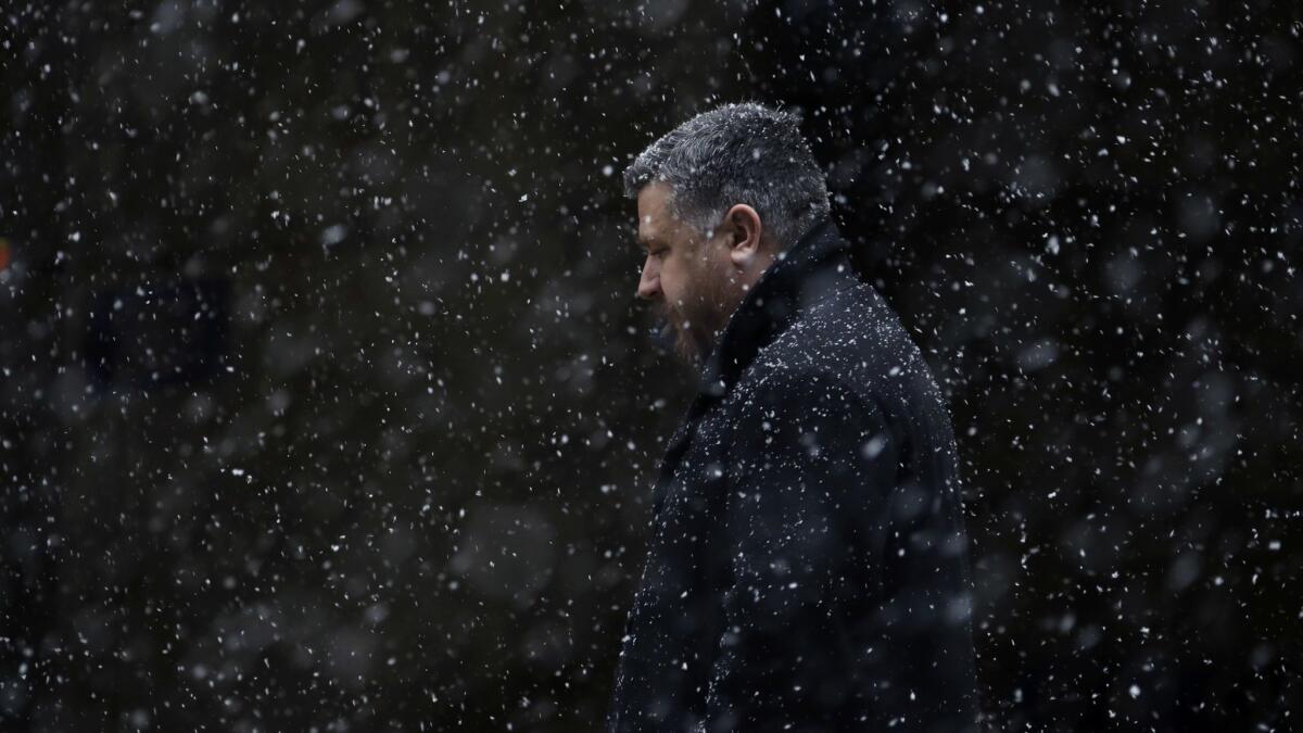 A man walks through falling snow Tuesday, March 20, 2018, in Philadelphia.