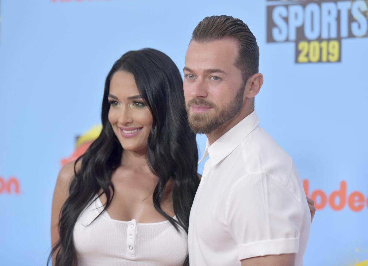 Nikki Garcia posing in a white tank top with Artem Chigvintsev wearing a short-sleeve white shirt