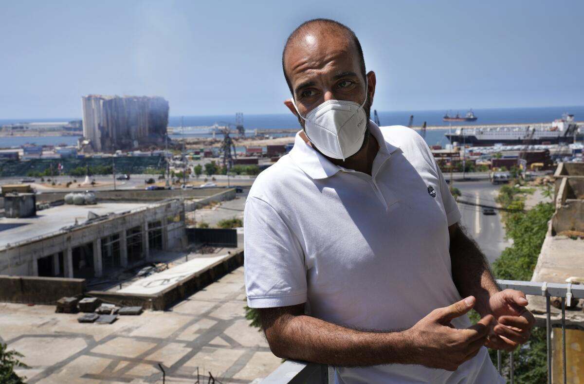 Johnny Assaf stands on his office balcony, with smoldering grain silos seen in the background