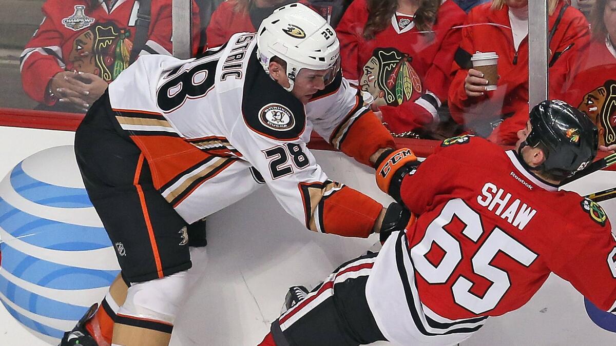 Ducks defenseman Mark Fistric, left, checks Chicago Blackhawks forward Andrew Shaw to the ice during a game on Oct. 28.
