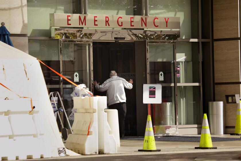 LOS ANGELES, CALIFORNIA-MARCH 18, 2020-An elderly man holds his hands up as if being questioned at the entrance to the emergency room at UCLA Medical Center. Testing for Covid-19 is going on at UCLA Medical Center. (Carolyn Cole/Los Angeles Times)