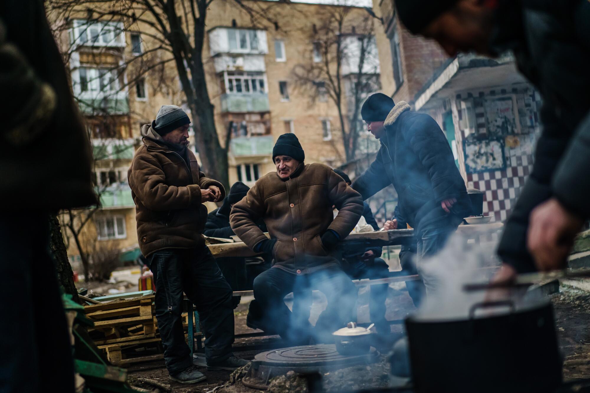 People gathered around steaming cookware