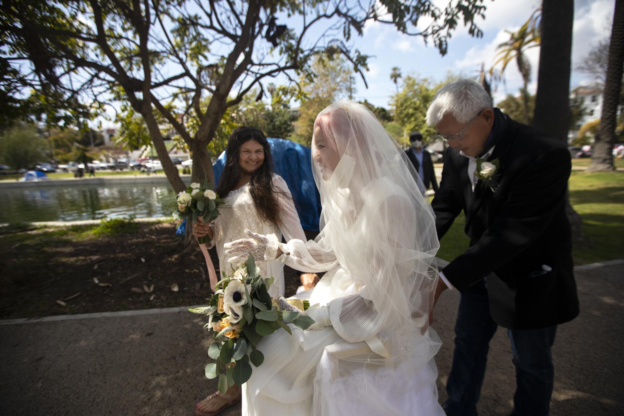 John Hsu pushes bride Valerie Zeller in a specially decorated wheelchair as her bridesmaid, Ana Vega, left, joins in.