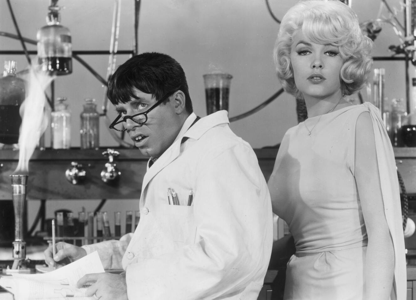 Jerry Lewis wears a lab coat and glasses as Stella Stevens poses next to him in a still from Lewis' film "The Nutty Professor" in 1963.