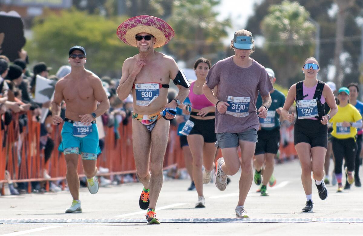 A runner wearing a sombrero and speedo approaches the finish line.