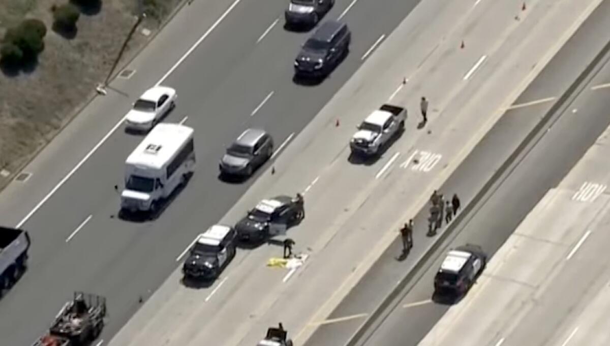 Cars are lined up on a freeway with police cars parked in a lane.