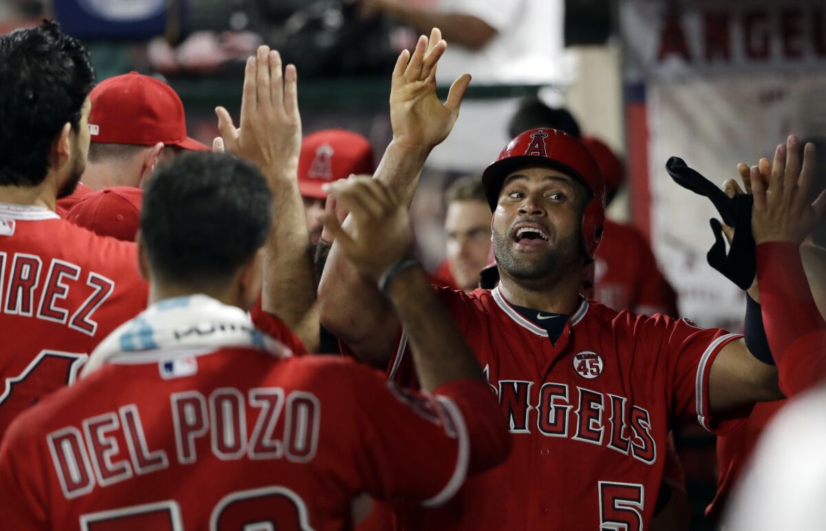 Angels slugger Albert Pujols celebrates in the dugout after scoring a run during the seventh inning against the Rangers on Tuesday.