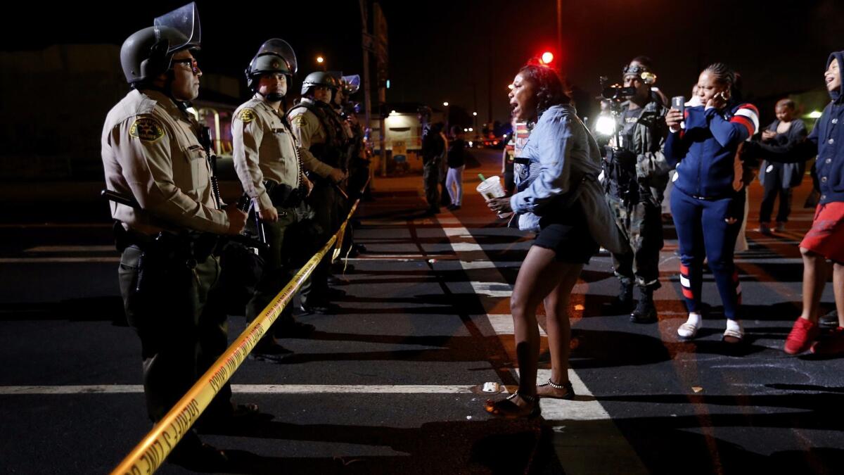 A woman confronts a line of Los Angeles County sheriff's deputies blocking the street after a vigil last year for Carnell Snell Jr., 18, who was fatally shot by LAPD officers.