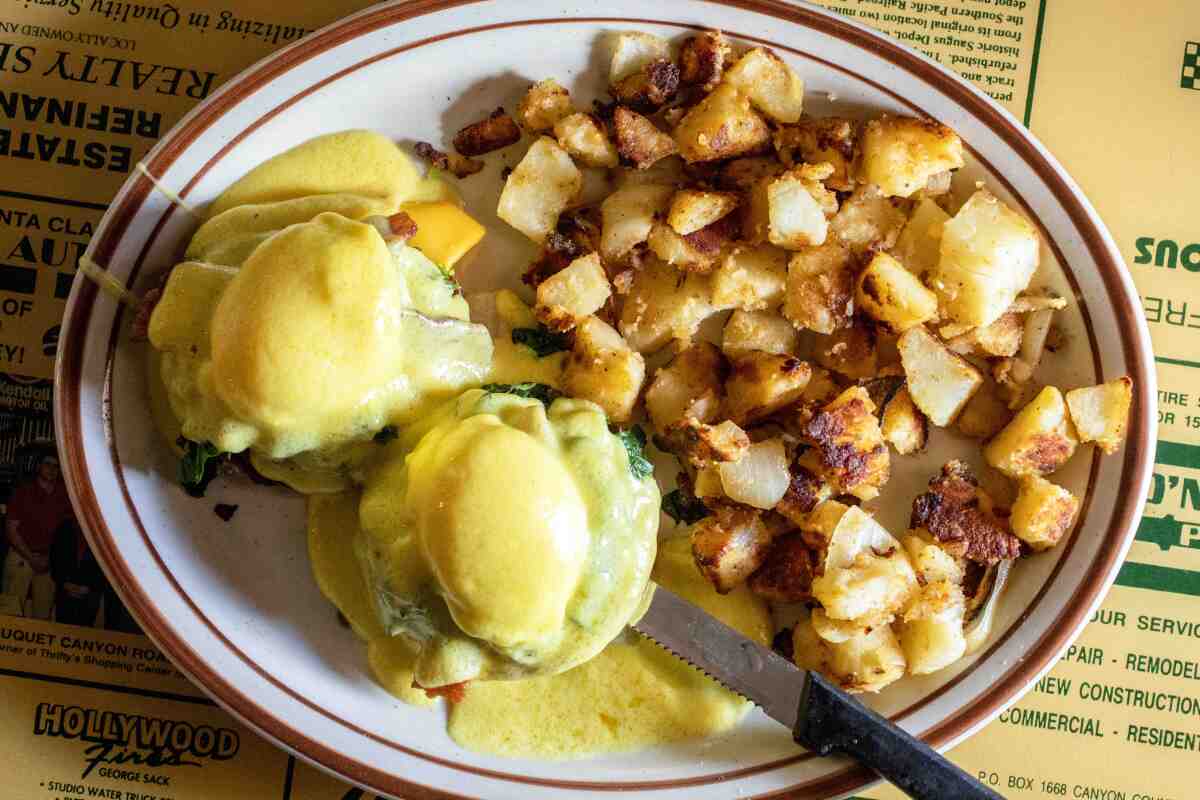Eggs benedict and potatoes on a plate.
