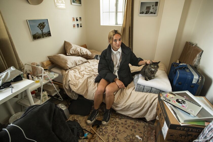 LINCOLN PARK, CA-MARCH 19, 2020: Khalilah Pianta, 30, a bartender at Lodge Room in Highland Park, is photographed with her cat Sunny, inside her bedroom at her home in Lincoln Park. Lodge Room, an independent live music venue, has had to cancel all shows until further notice, due to the coronavirus outbreak, leaving Pianta without a job since March 14, 2020. (Mel Melcon/Los Angeles Times)