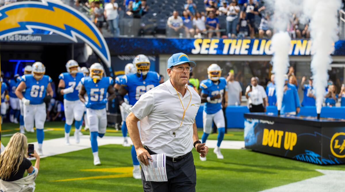 Chargers coach Jim Harbaugh runs onto the field before a preseason game against the Rams.