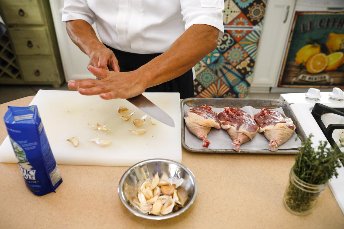 Chef Bruno Albouze prepares the duck before cooking, adding garlic, salt and thyme.