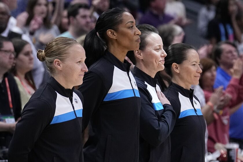 An all-women officiating crew stands at mid court during the national anthem before an NCAA Women's Final Four semifinals basketball game between LSU and Virginia Tech Friday, March 31, 2023, in Dallas. (AP Photo/Tony Gutierrez)