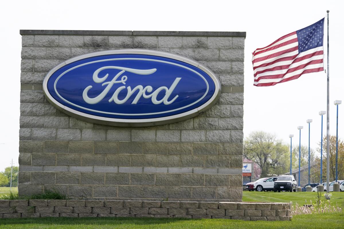 Una bandera estadounidense ondea junto a una concesionaria Ford