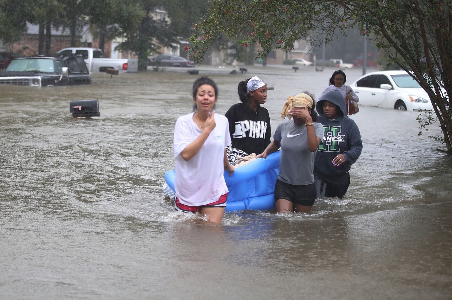 Evacuees walk down a flooded street after leaaving their homes Monday in Houston.
