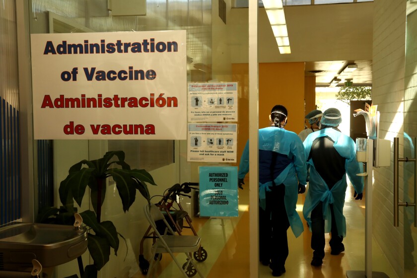 A clinic sign reads "Administration of Vaccine" in English and Spanish.