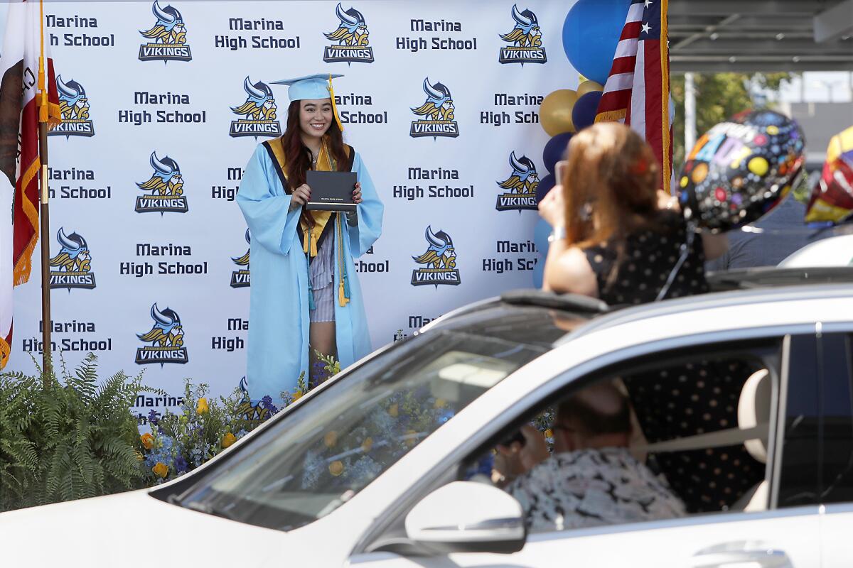 Katherine Dillman poses with her diploma during a drive-through graduation ceremony for Marina High.