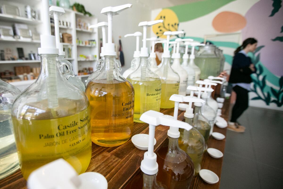 Large containers of liquid beauty and cleaning products at a refill station