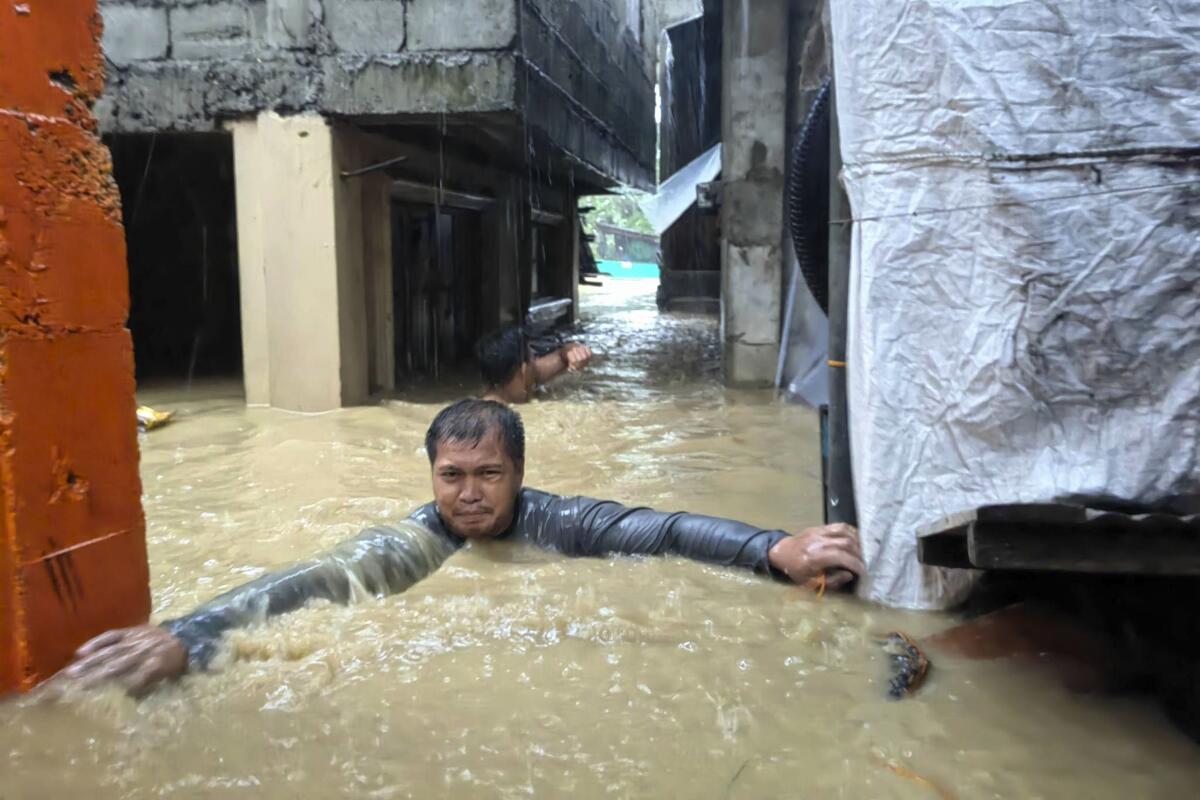 A man tries to move through neck-deep floodwaters.