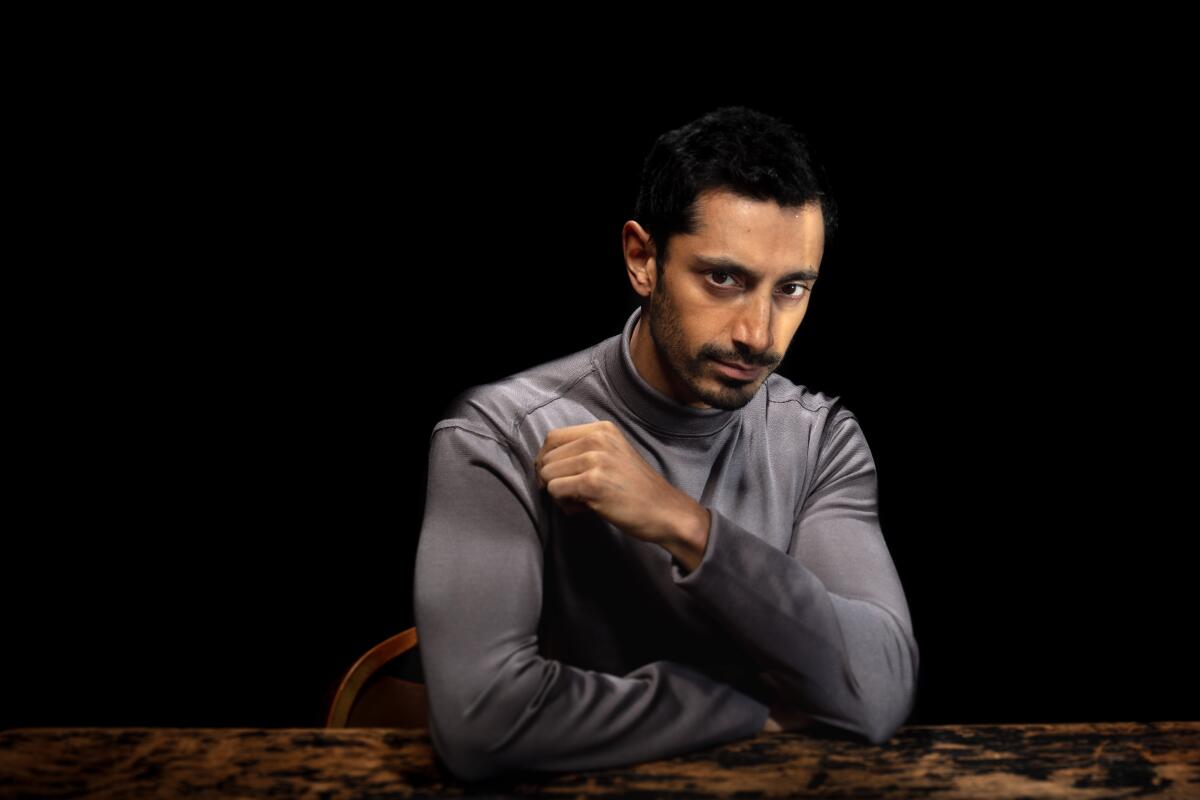 Actor Riz Ahmed sits in a dark room