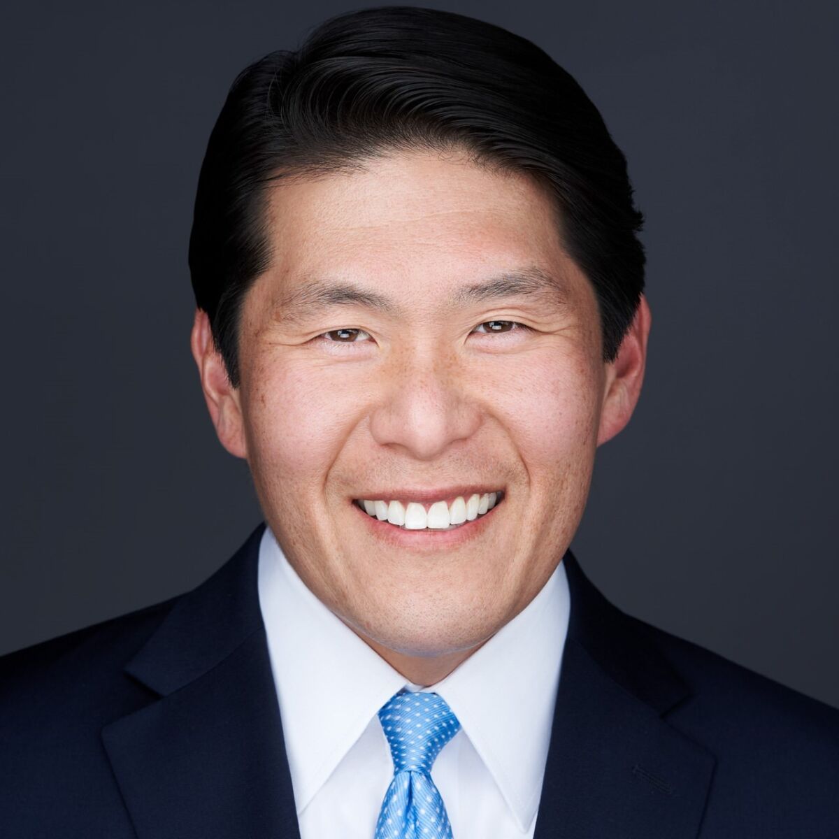 A portrait of a man in a suit and tie, smiling