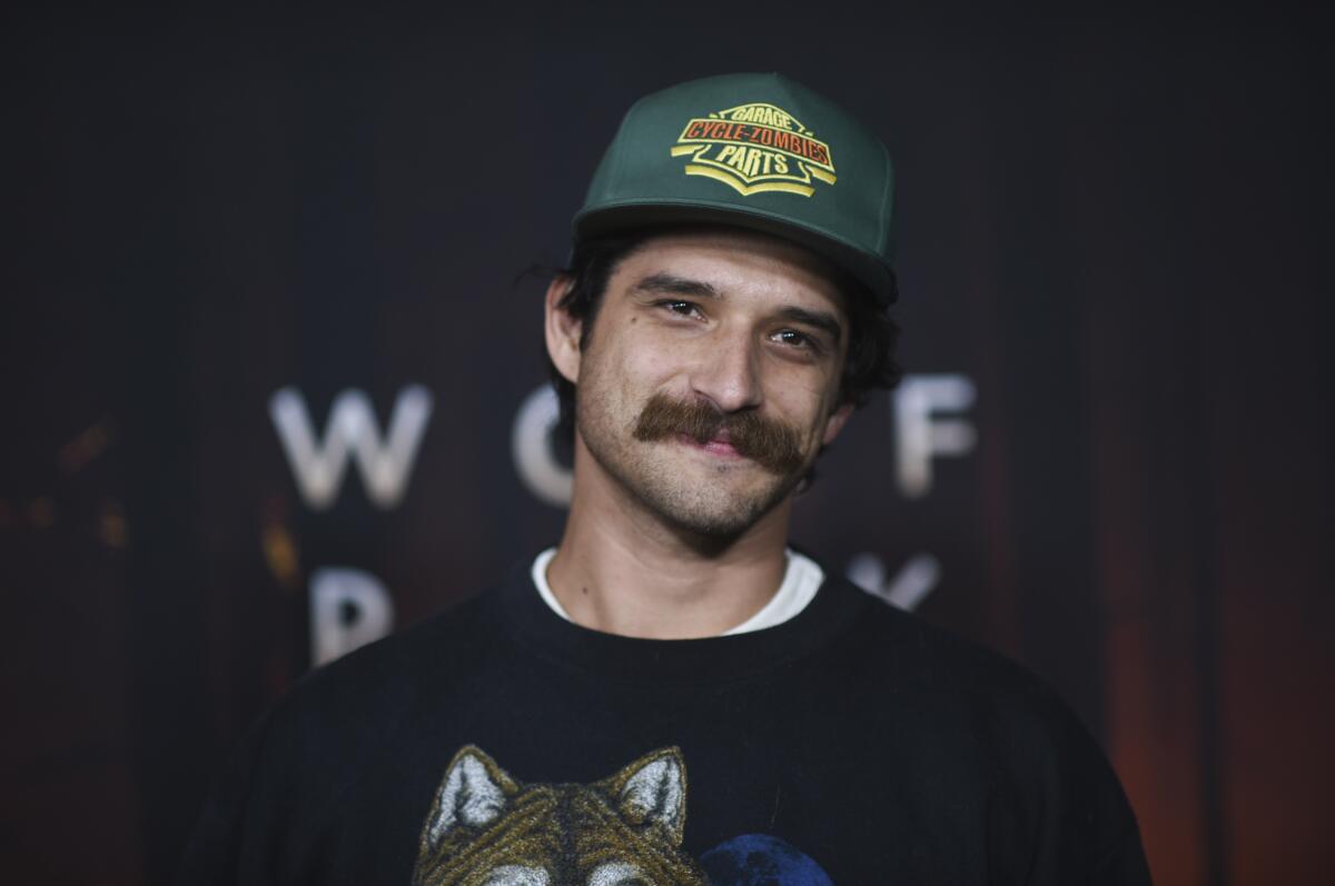 Tyler Posey sports a mustache and poses in trucker hat