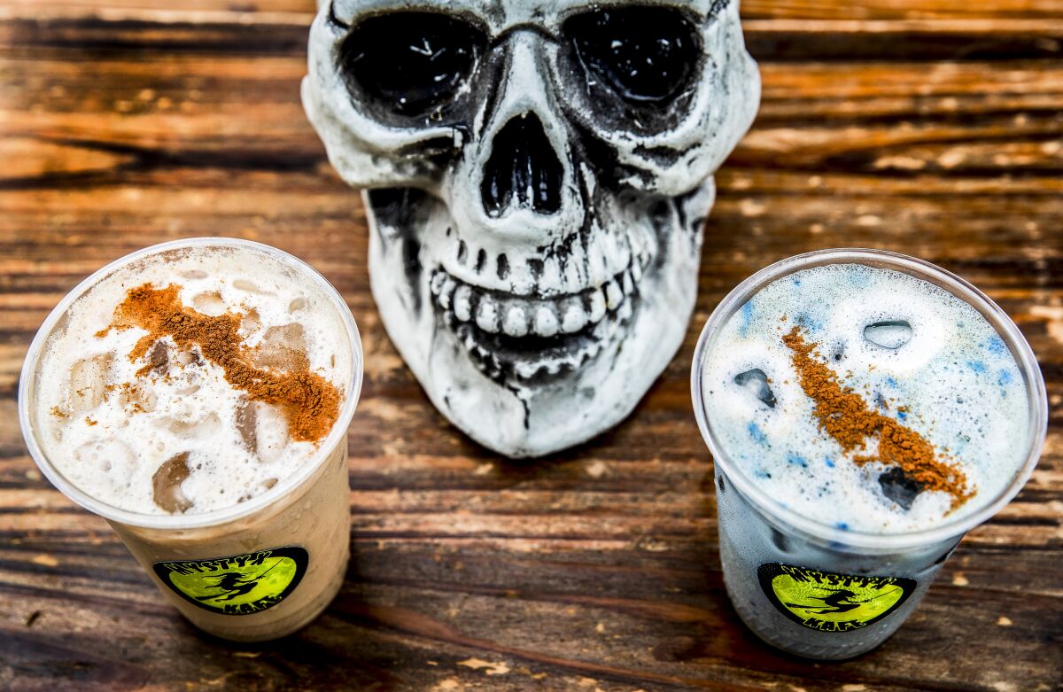 A fake skull decoration sits between two iced drinks in plastic cups.