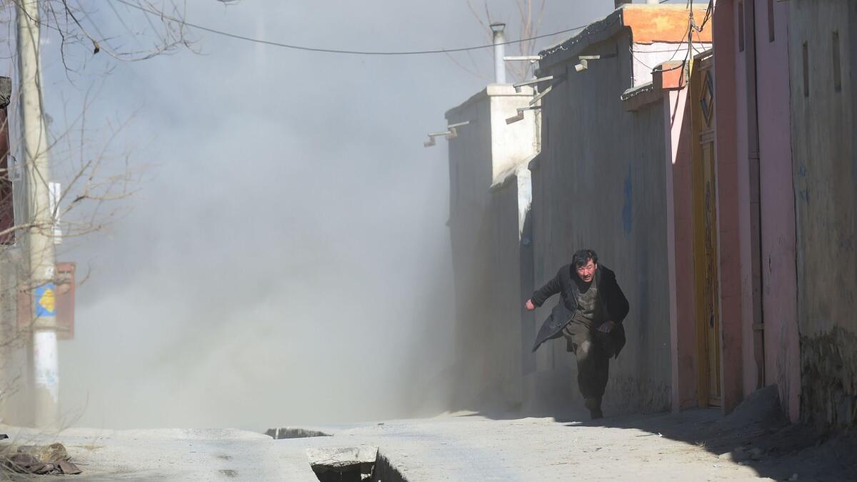 An Afghan man runs away as dust blows in the aftermath of the third blast at a Shiite cultural centre in Kabul on December 28.