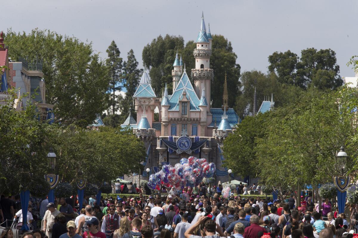 A large crowd strolls down Disneyland's Main Street on its 60th anniversary in June.