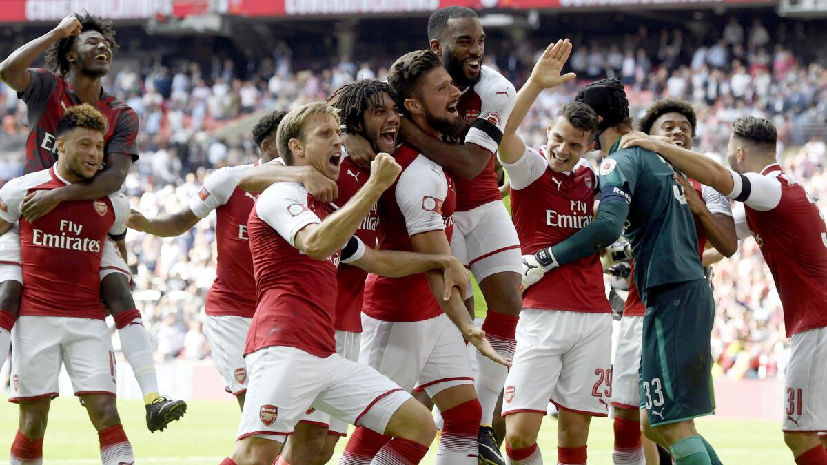Arsenal's Olivier Giroud is mobbed by teammates after scoring the winning penalty shot during the FA Community Shield against Chelsea on Sunday.