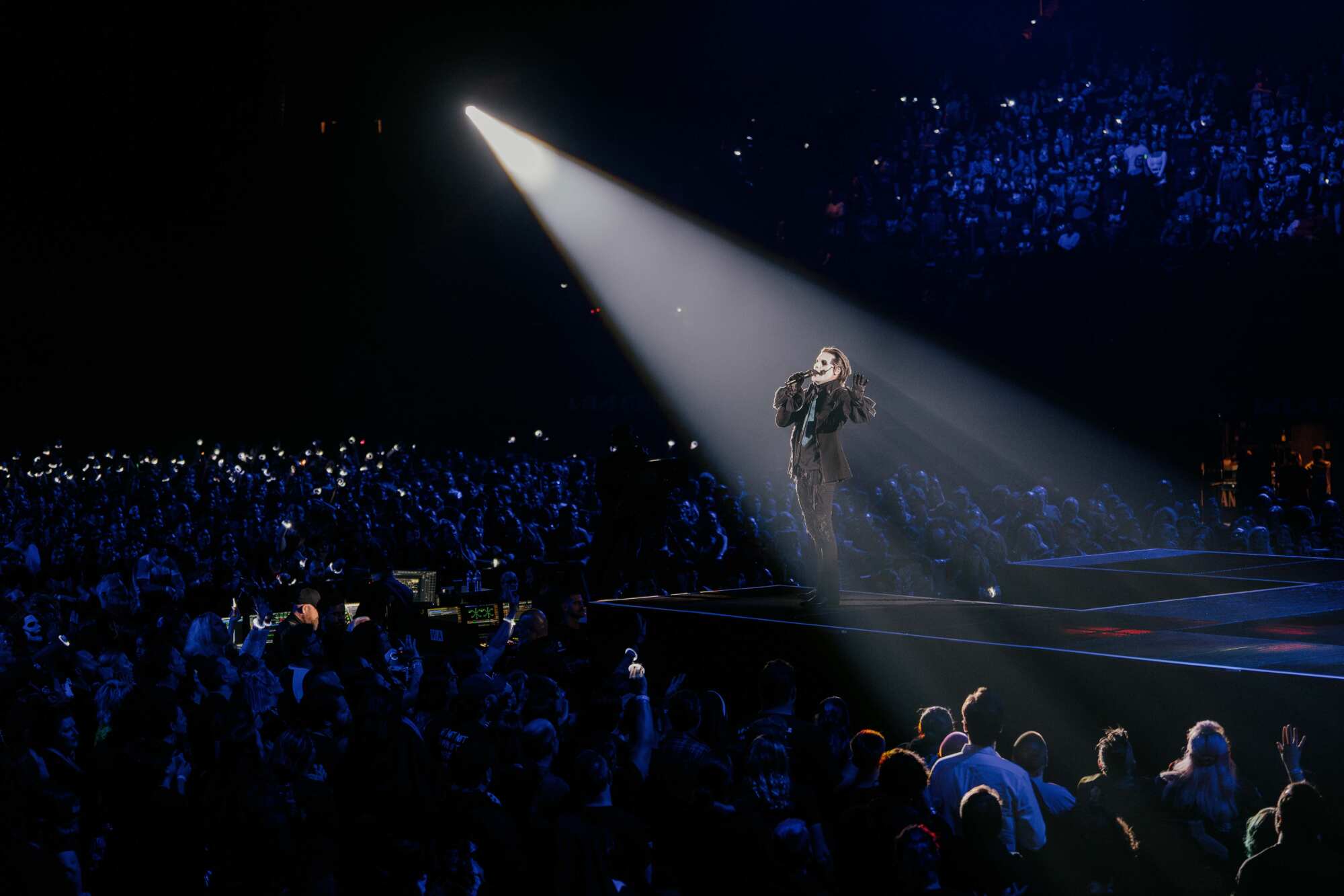 A singer in a spotlight performs in front of a large crowd.