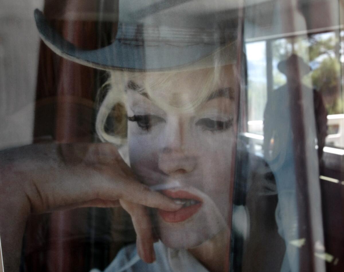 The outline of a person is reflected in a photo of Marilyn Monroe in which she wears a cowboy hat and a pensive look.