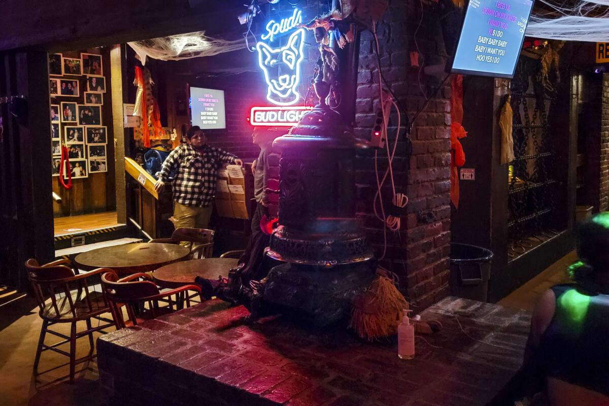 The common area at Cafe Brass Monkey karaoke bar features a Spuds Bud Light neon sign.