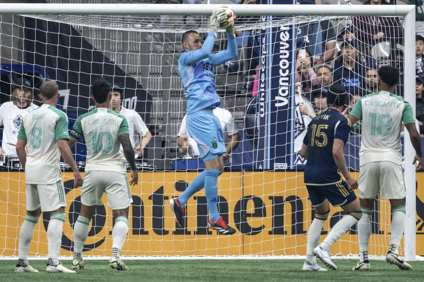 Austin FC goalkeeper Brad Stuver stops the ball as Alexander Ring (8), Sebastian Driussi (10), Julio Cascante (18) and Vancouver Whitecaps' Bjorn Utvik (15) watch during the first half of an MLS soccer match in Vancouver, British Columbia, on Saturday, May 4, 2024. (Ethan Cairns/The Canadian Press via AP)