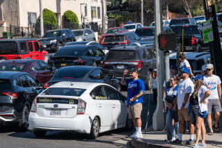 Los Angeles Dodgers fan walk alongside a road packed with vehicle traffic.