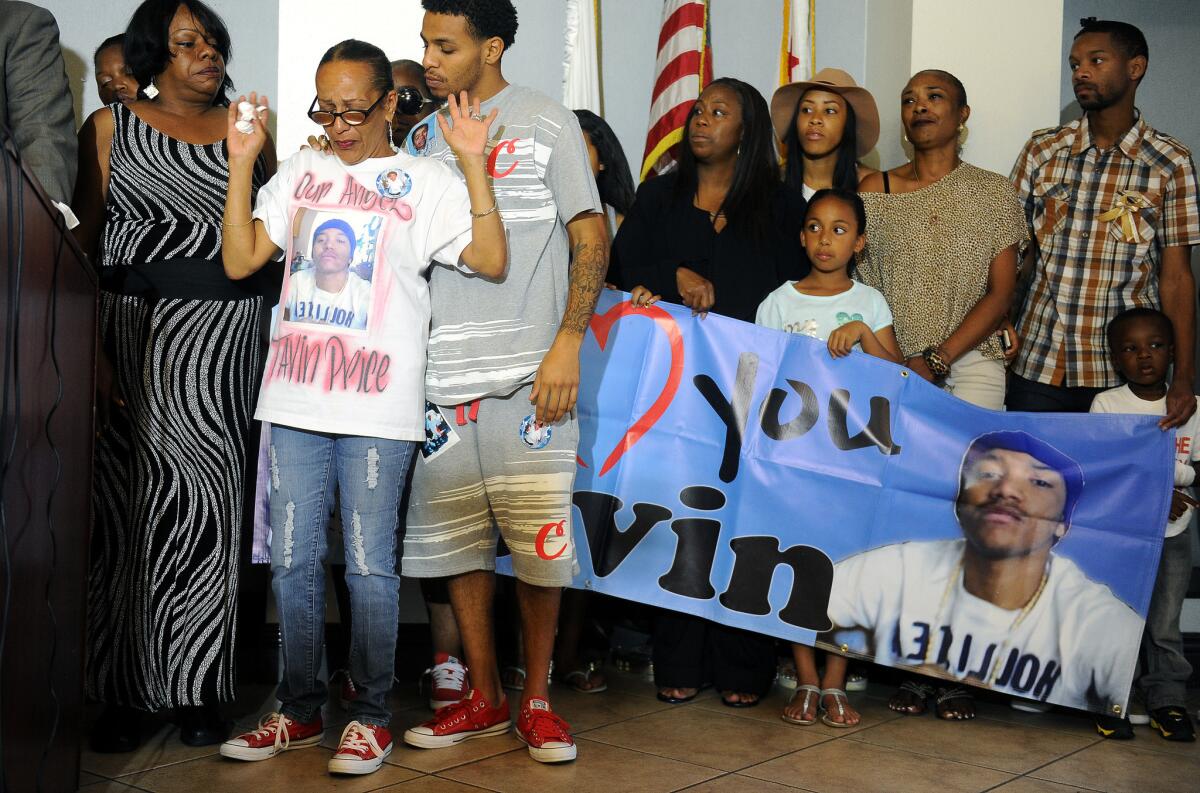 Surrounded by family, Jennifer Rivers, second from left, raises her arms in relief during the announcement by LAPD detectives of the multiple arrests made in the slaying of Rivers' son Tavin Price, who was shot May 29 on West Florence Avenue.
