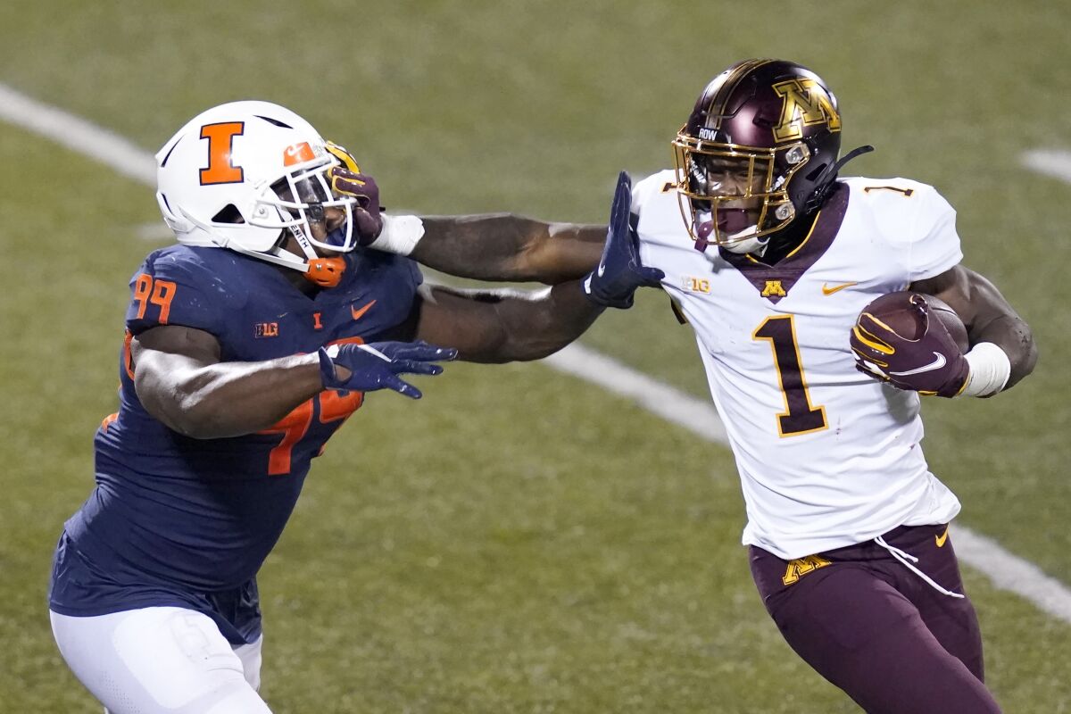 Minnesota running back Cam Wiley (1) stiff arms Illinois defensive lineman Owen Carney Jr. during the second half of an NCAA college football game Saturday, Nov. 7, 2020, in Champaign , Ill. Minnesota won 41-14. (AP Photo/Charles Rex Arbogast)