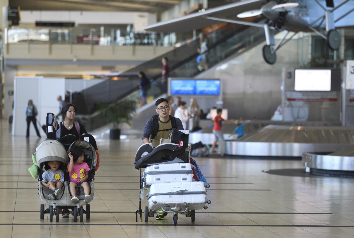 Travelers leaving baggage claim area of airport