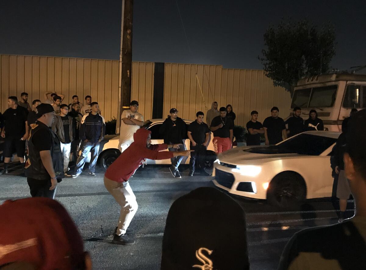 Car enthusiasts, including Brotherhood members, take in the action as an early morning street race is set to begin in a South Los Angeles neighborhood in September 2018.