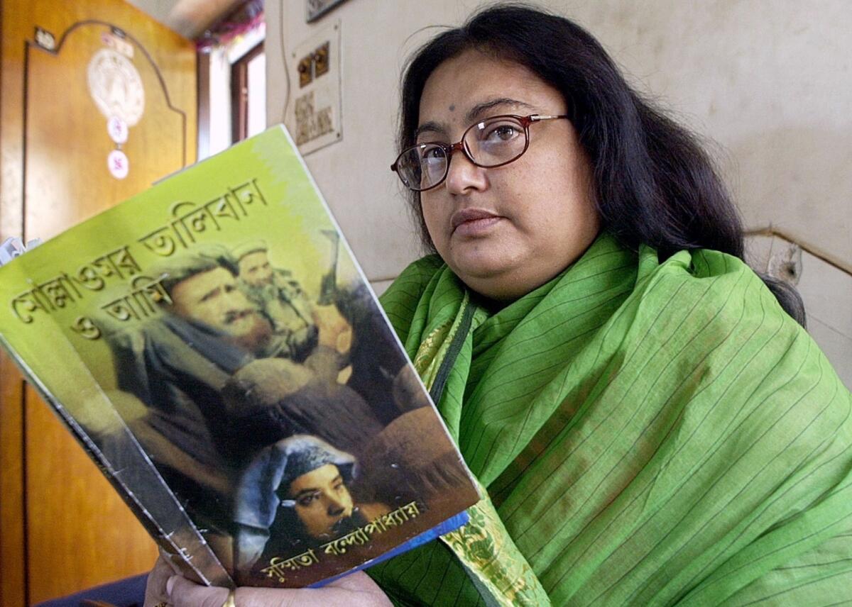 Indian author Sushmita Banerjee holds one of her Bengali-language novels, "Mullah Omar, Taliban and Me," in Kolkata.