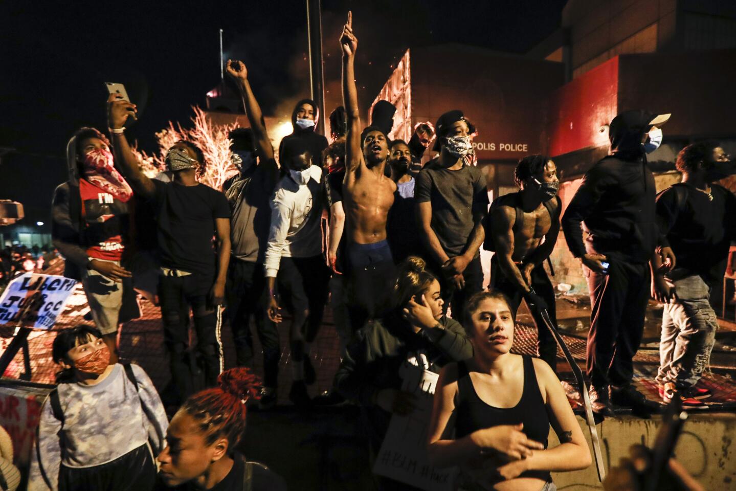 Protesters demonstrate outside a burning Minneapolis 3rd Police Precinct on Thursday