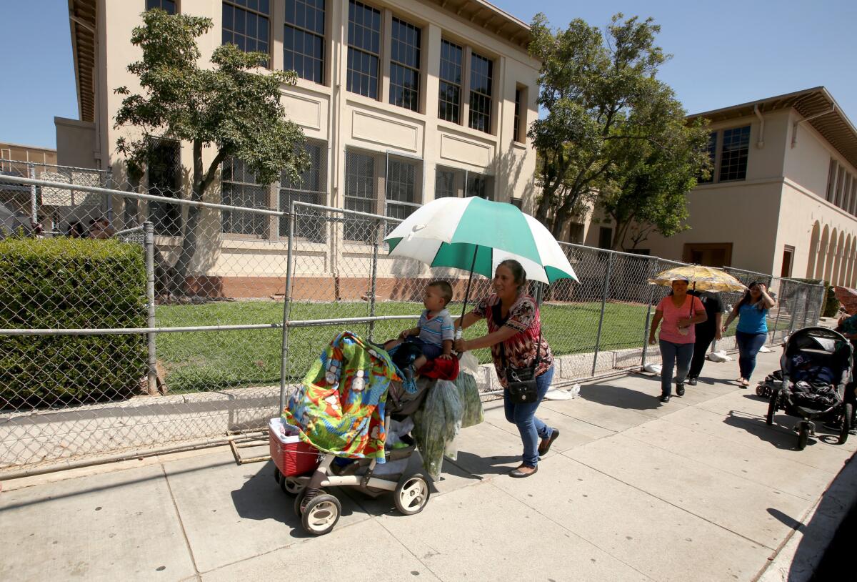 Padres de familia recogen a sus hijos en la escuela Rowan Avenue, en el Este de Los Ángeles. Este fue uno de los tres centros escolares con cercas metálicas que instaló el LAUSD para alejar a los estudiantes del suelo contaminado que ha causado la planta Exide en el sureste del condado.