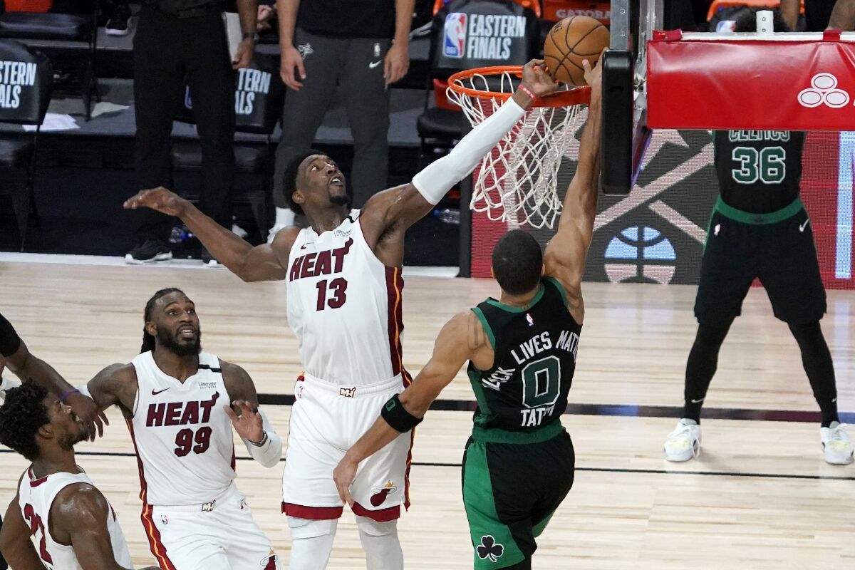 Miami Heat's Jimmy Butler and Jae Crowder look on as Bam Adebayo blocks a shot attempt by Boston Celtics' Jayson Tatum.