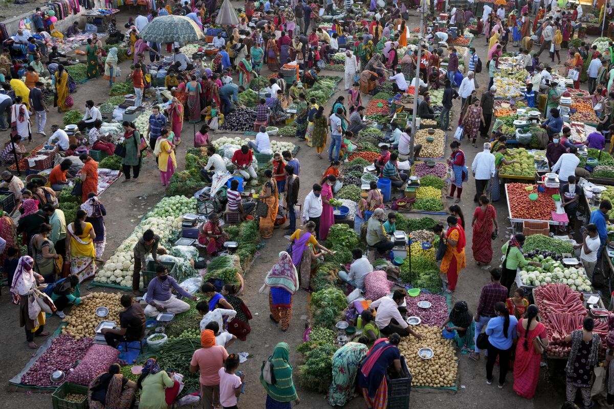 Shoppers buy produce at an open air market in Ahmedabad, India, Thursday, March 3, 2022. Slowly but steadily, life in South Asia is returning to normal, and people hope the worst of the COVID-19 pandemic is behind them. Experts are optimistic that the omicron surge, which brought relatively low levels of death, has reinforced immunity from vaccines, which are widespread in the region. (AP Photo/Ajit Solanki)